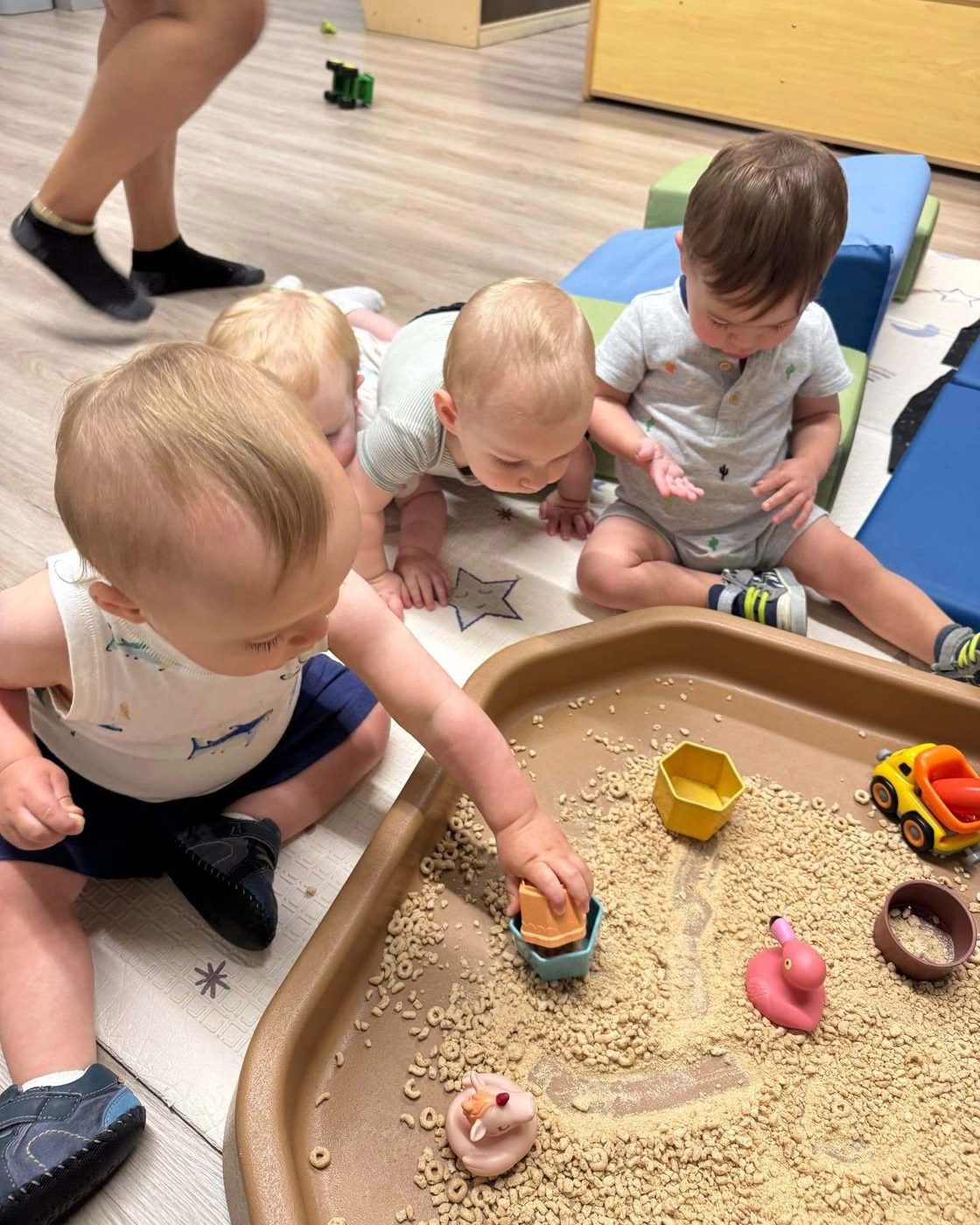 Infants exploring a sensory table in the World of Wonder infant room